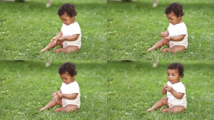 一个六个月大的非裔美国黑人小孩在夏天的草地上爬着玩草