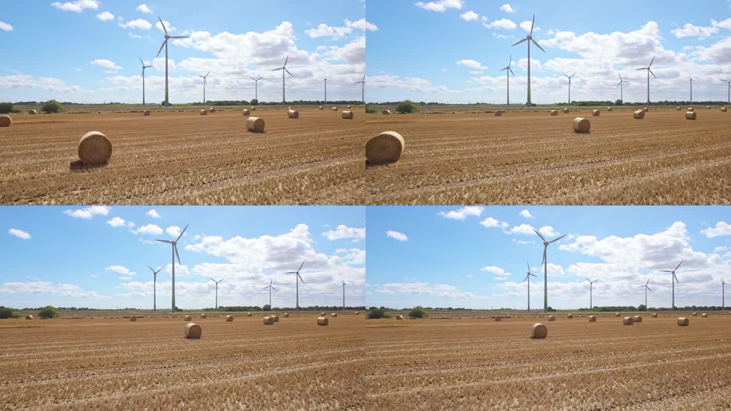 在林肯郡的乡村上空，我们看到一系列的风力涡轮机在农民刚刚收割的田地里旋转，金色的干草捆点缀着风景。