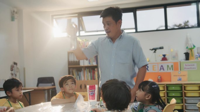 一位亚洲男教师在科学课上给小学生们推荐科学实验设备。
