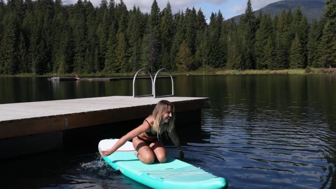 女子划桨板(SUP)穿过宁静的湖泊