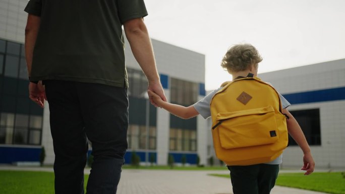 孩子和父母早上去学校，小男孩牵着父亲的手的背影