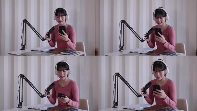 快乐的亚洲妇女设置播客工作室戴着耳机，用麦克风录制播客，在智能手机上阅读新闻，在家庭工作室进行广播在