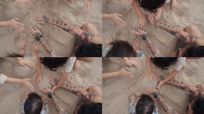 暑假期间一家人在海滩上堆沙堡的俯视图。
