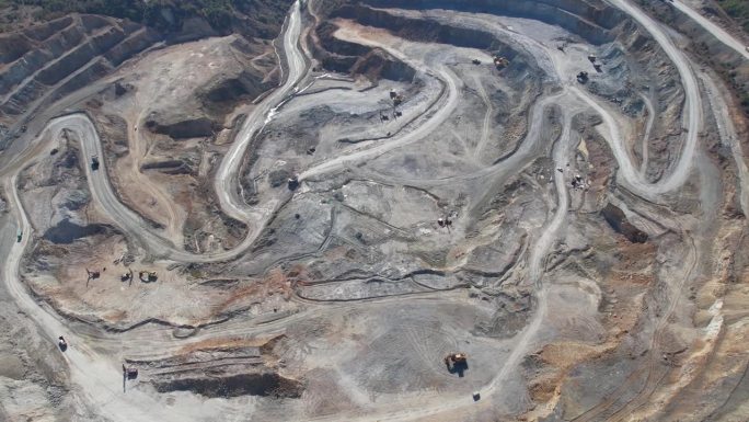 露天矿坑内大量机械、挖掘机和卡车的景象