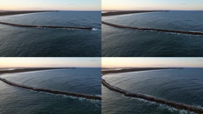 在澳大利亚新南威尔士州伊卢卡的伊卢卡海滩和断头墙上的日落。航拍盘左