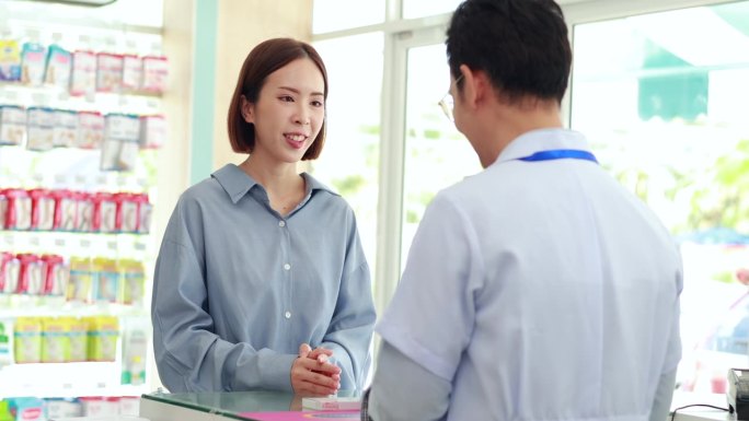 咨询，医药信息，亚洲女性客户或患者。亚洲男药剂师在药房讲解如何正确服药治疗疾病。卫生保健中心