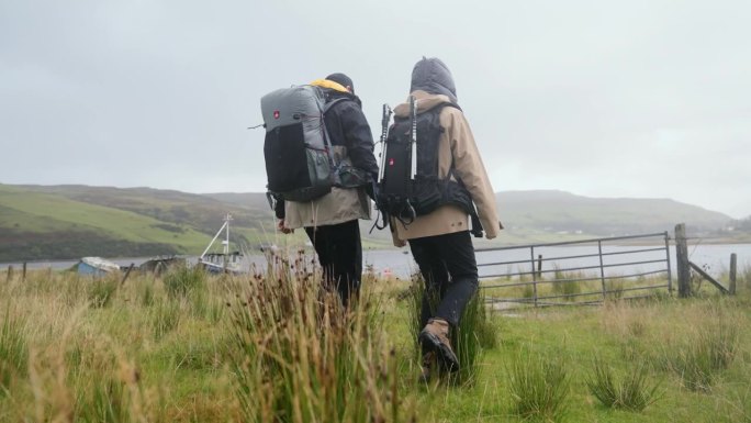 两个人一起用北欧拐杖徒步旅行。正朝栅栏和大门走去