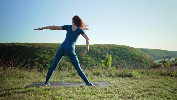 一位女瑜伽士在高山之巅做瑜伽练习——在深呼吸的情况下做三角体式。野性的自然，自由的人类。自由，健康的