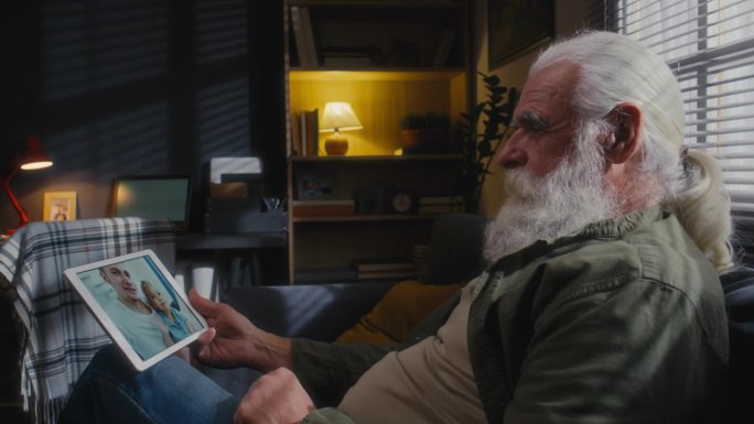老人拿着平板电脑和儿子孙女聊天
