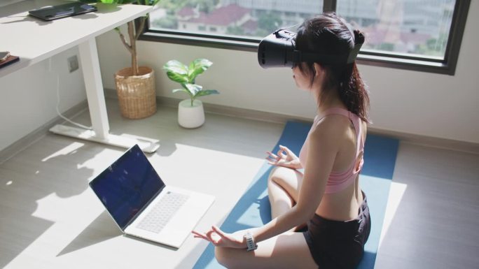 亚洲运动女性做瑜伽虚拟现实练习
