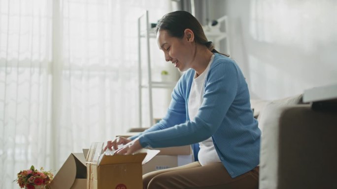亚洲女子在网上购物时打开纸箱，跟踪镜头