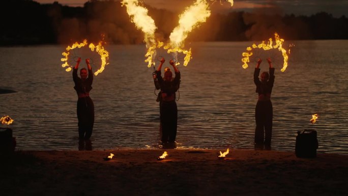日落后，一群手持火把的女艺术家在海滩上表演火焰表演
