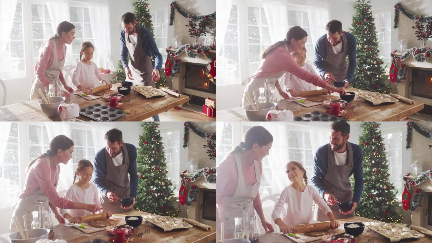 圣诞快乐的家庭:年轻的父母和他们可爱的小女儿在家里一起准备糕点的慢动作肖像。可爱的家庭准备节日晚餐，