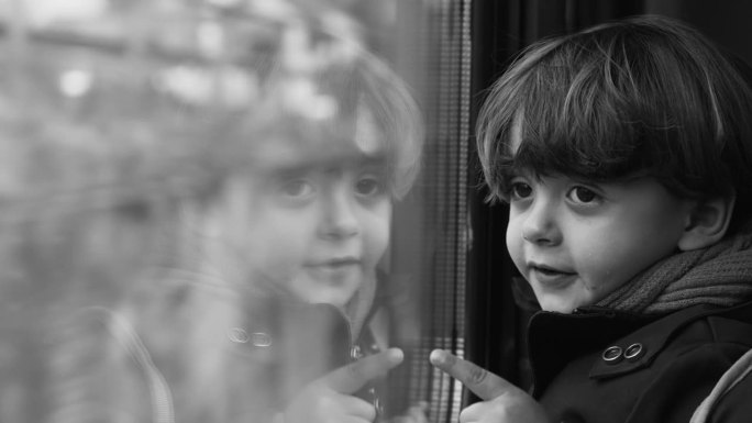单色沉思的孩子凝视着从高速列车上经过的风景，黑白剪辑的沉思的孩子旅行者