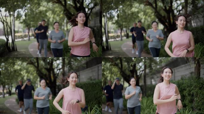 在一个温暖的日子里，女儿妈妈、爸爸和儿子在公园里慢跑的慢动作广角跟踪镜头。