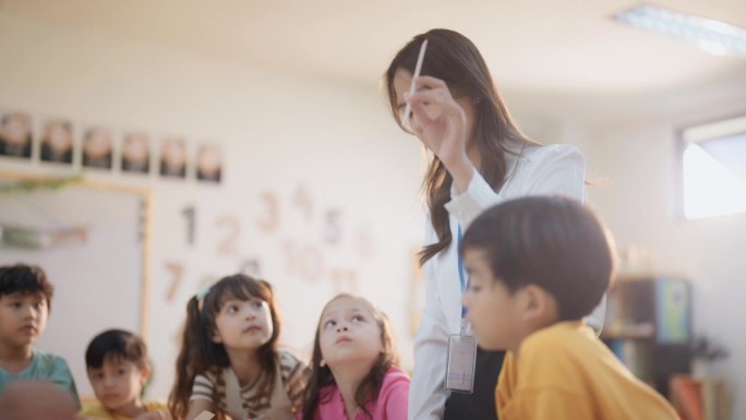 学生在课堂上和老师一起学习。美丽的女老师在幼儿园用快乐有趣的活动讲解和教育孩子