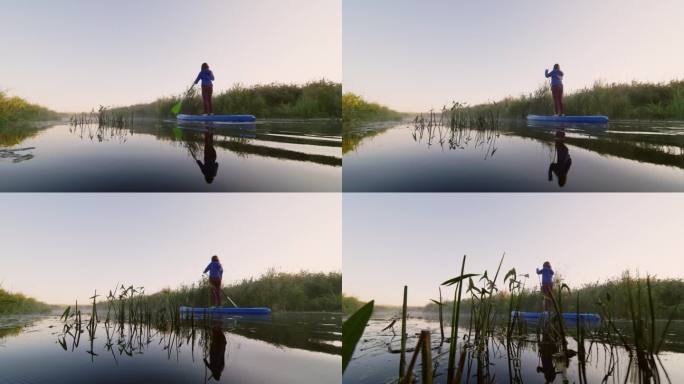 女子划着桨沿着长长的河流在SUP板上移动