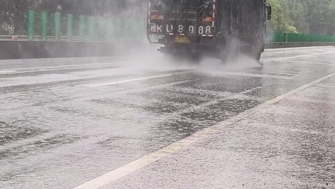 公路雨天行驶的大货车通过雨水积水路段