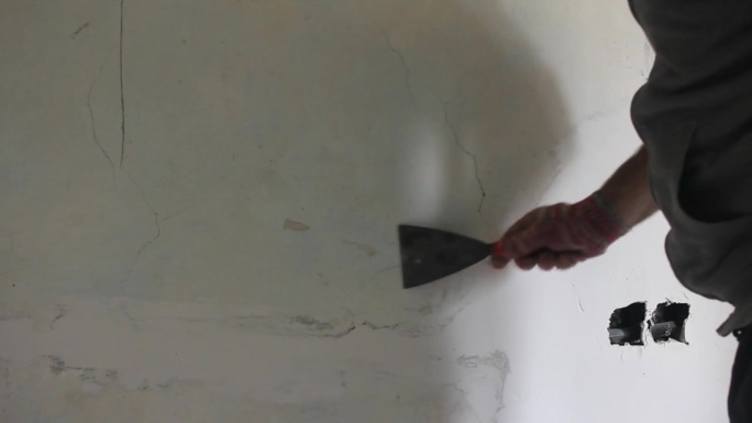 一个人在用刮刀刮墙