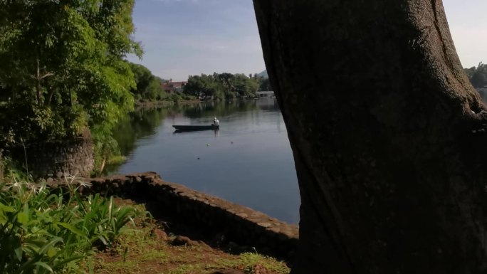 面目全非的湖上船夫操纵着他的木排船渡过湖面。树遮住了视野。模糊了