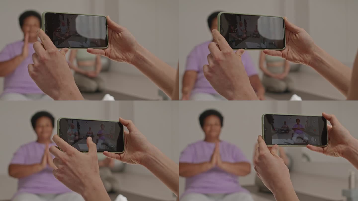 用智能手机拍摄集体瑜伽练习的女性之手