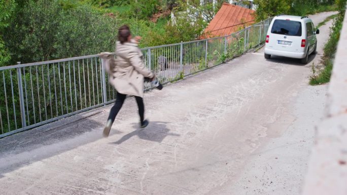 穿大衣的人在狭窄的道路上追赶一辆白色的汽车