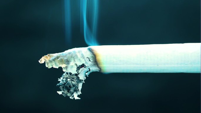 香烟燃烧缓慢释放毒素在空气中影响周围的人与疾病和疾病静止不动蓝色的烟灰从烟卷白色的纸被烧黑可怕
