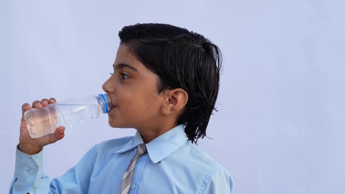 印度学校的孩子们在喝水。一个可爱的孩子从白色的可重复使用的瓶子里喝水