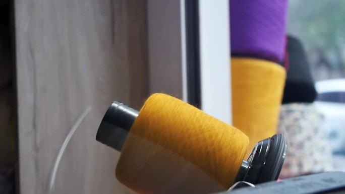 橘色毛纱用自动绕线机缠绕在绞纱上。缝纫、针织生产。纱线零售业