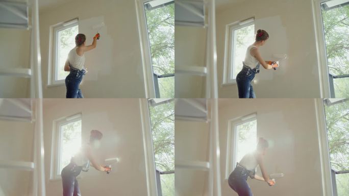 一个女人用滚轴粉刷她梦想中的房子的墙壁。穿戴防护服和护目镜