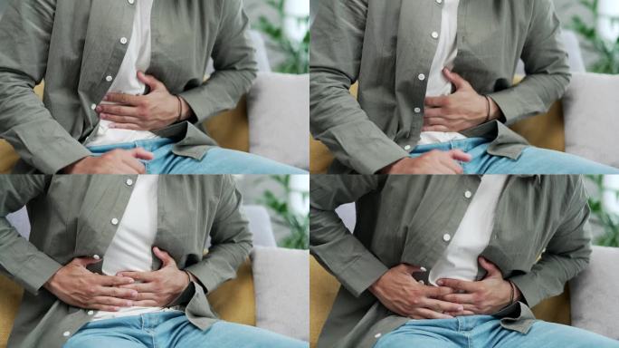 近景短发男子双手按摩腹部，坐在沙发上感觉突然强烈的腹部疼痛，胃炎的问题