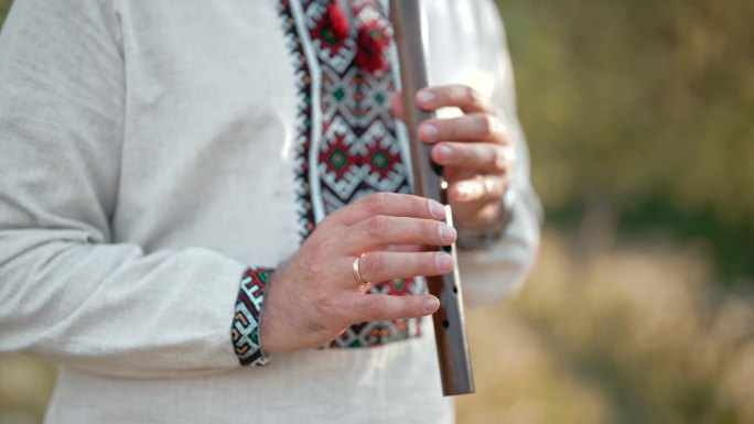 年轻人的手在户外演奏木管木笛-乌克兰索皮卡。民间音乐概念。乐器。身穿传统刺绣衬衫的音乐家。