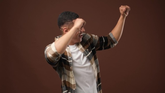快乐的年轻非洲裔美国人跳舞在棕色的工作室背景