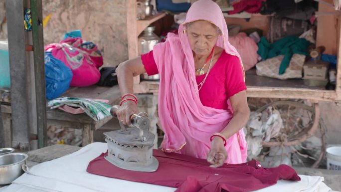 一位年长的印度妇女正在熨衣服