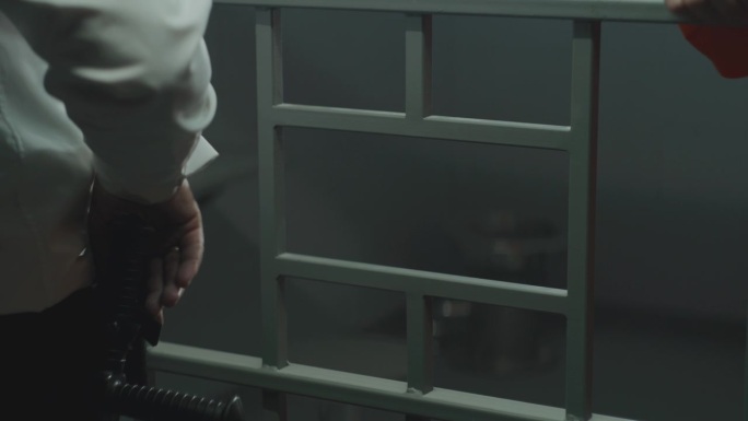 狱卒将手机隔着铁栏杆交给罪犯的特写镜头