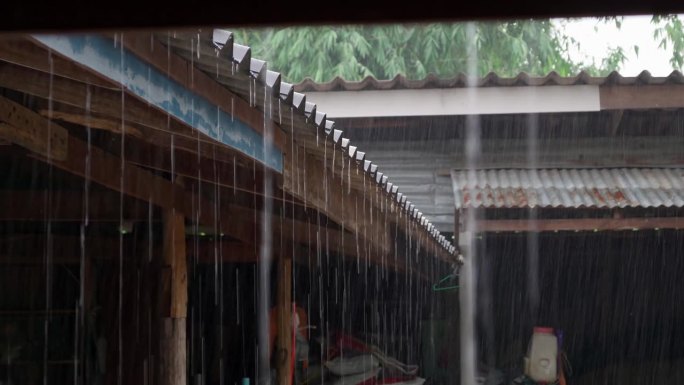 雨下得很大，雨水从农村房屋的屋顶上流下来。泰国暴雨造成暴雨，雨水从屋顶流下