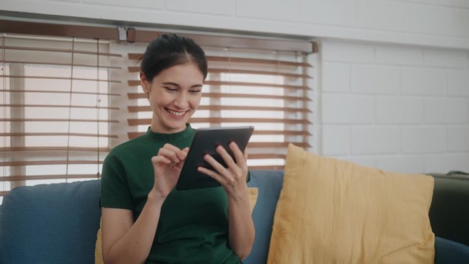 幸福与联系:舒适沙发上使用平板电脑的多元女性——拥抱现代科技的乐趣。