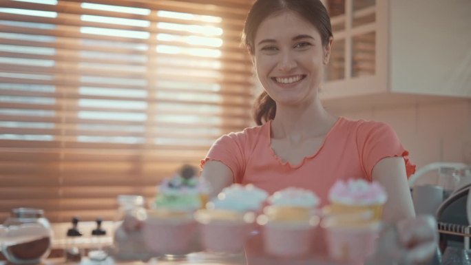 女人在不锈钢烤架上微笑着展示新鲜的纸杯蛋糕，慢镜头
