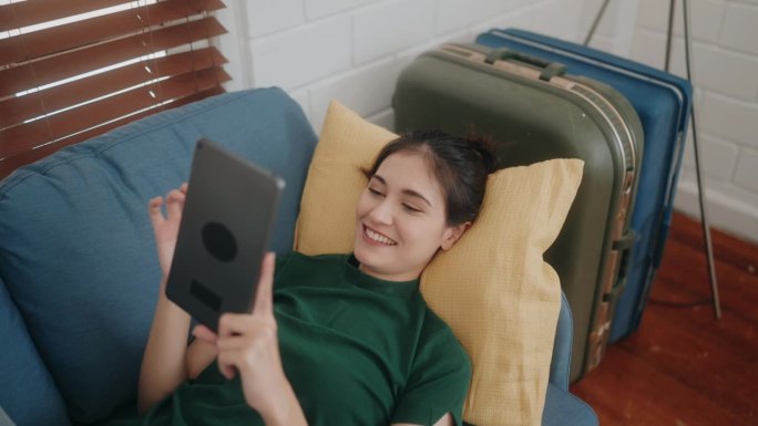 拥抱现代生活方式:年轻女性用平板电脑上网，在家沙发上休闲。