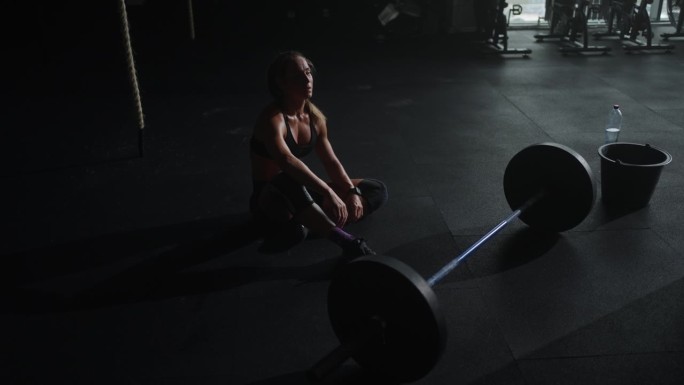 女运动员在艰苦的力量训练后休息，在健身房有动力的女举重运动员的肖像