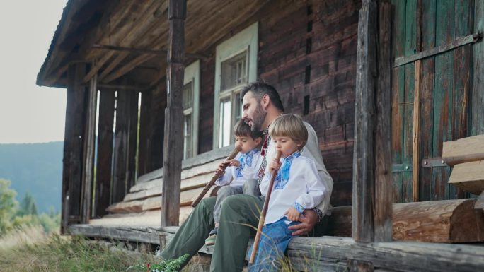 小男孩们和爸爸一起演奏木管木笛——乌克兰索皮尔卡。家庭，民乐概念。父亲和儿子穿着传统的刺绣衬衫。他们