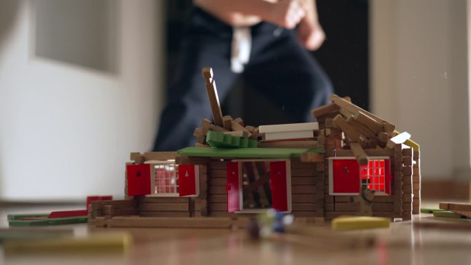 儿童破坏房屋建筑模型。孩子把木头模型踢回家。小男孩小男孩行为不端，教育童年观念