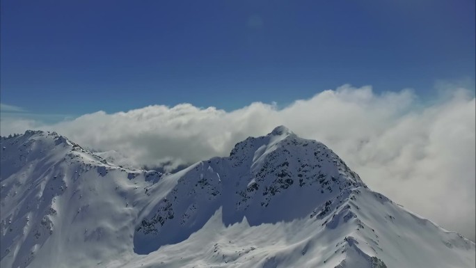 鸟瞰雪山峰顶，云雾笼罩着蓝天。
