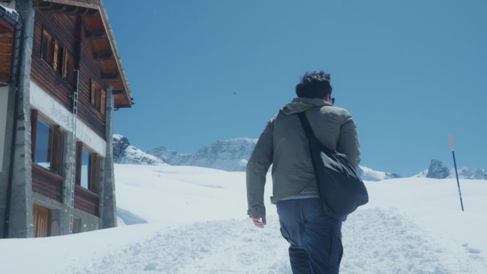 一个快乐的年轻人的后视图，她在瑞士雪山度假的空闲时间散步和拍照。