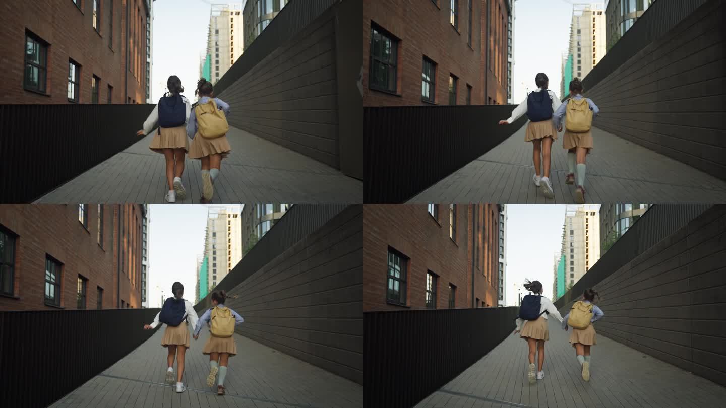 两个女学生上学的后视图。同学们背着书包在学校大楼前。