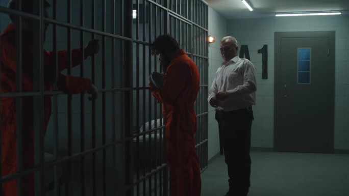 狱警把穿橙色制服的罪犯锁在牢房里