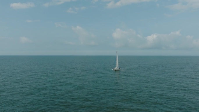 航拍一艘白色的帆船在平静的波罗的海，白色的帆船在茫茫大海的中央，阳光明媚的夏日，宽做轨道拍摄