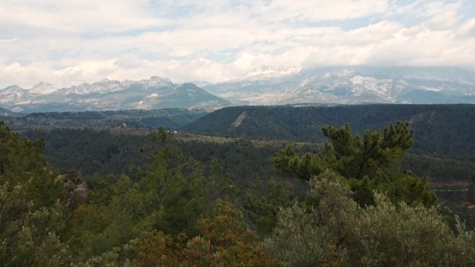 在土耳其，一架无人机飞过两名站在一起的游客，背景是风景优美的山区，天空多云。旅游、旅游、自然风光拍摄