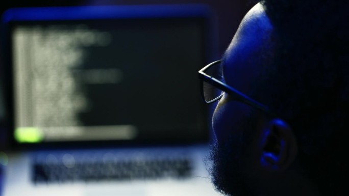 男性电脑黑客在家里的暗室里编程