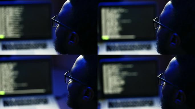 男性电脑黑客在家里的暗室里编程